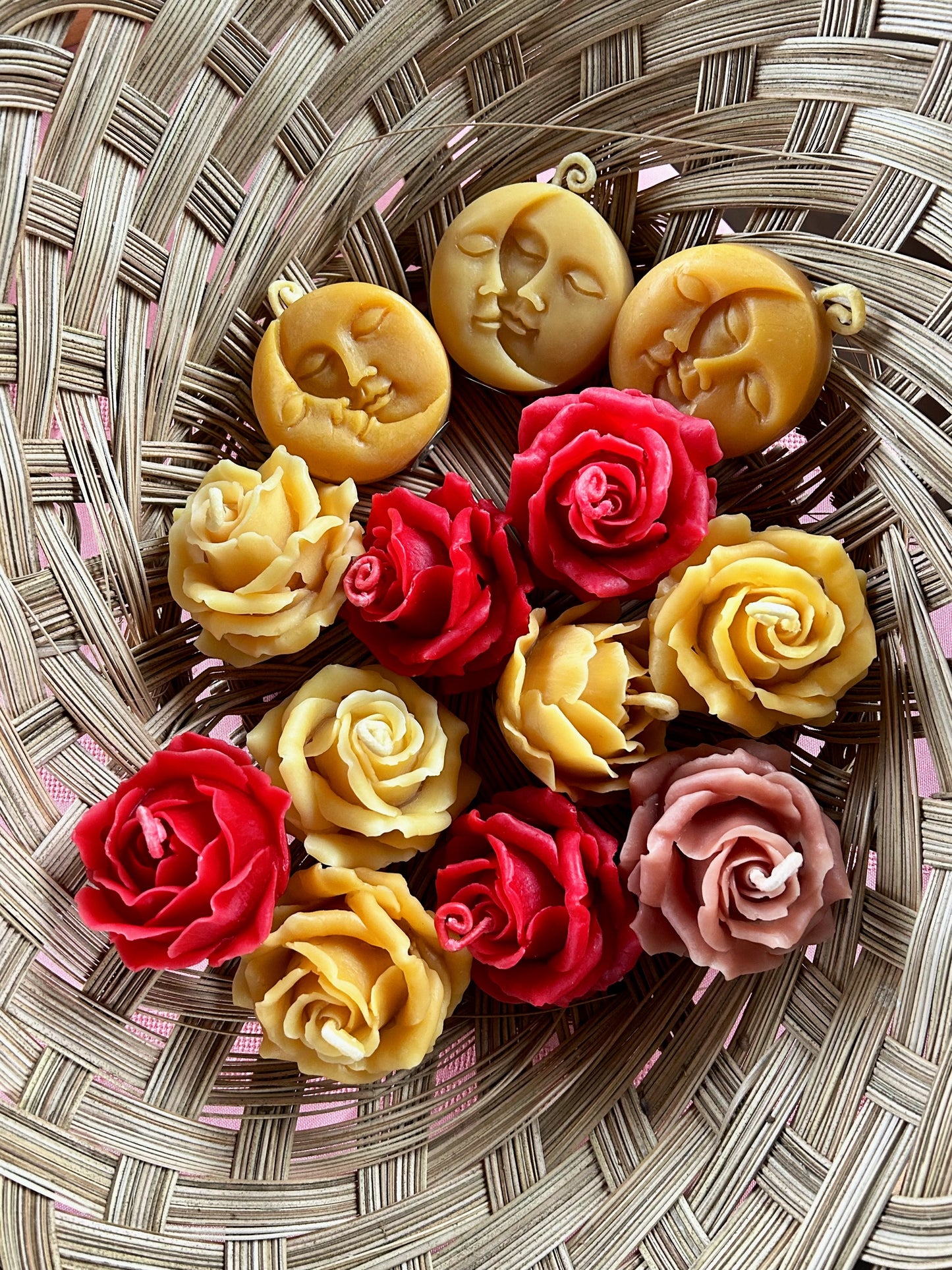 Assorted beeswax  rose candles and sun moon beesweax candles in a basket.