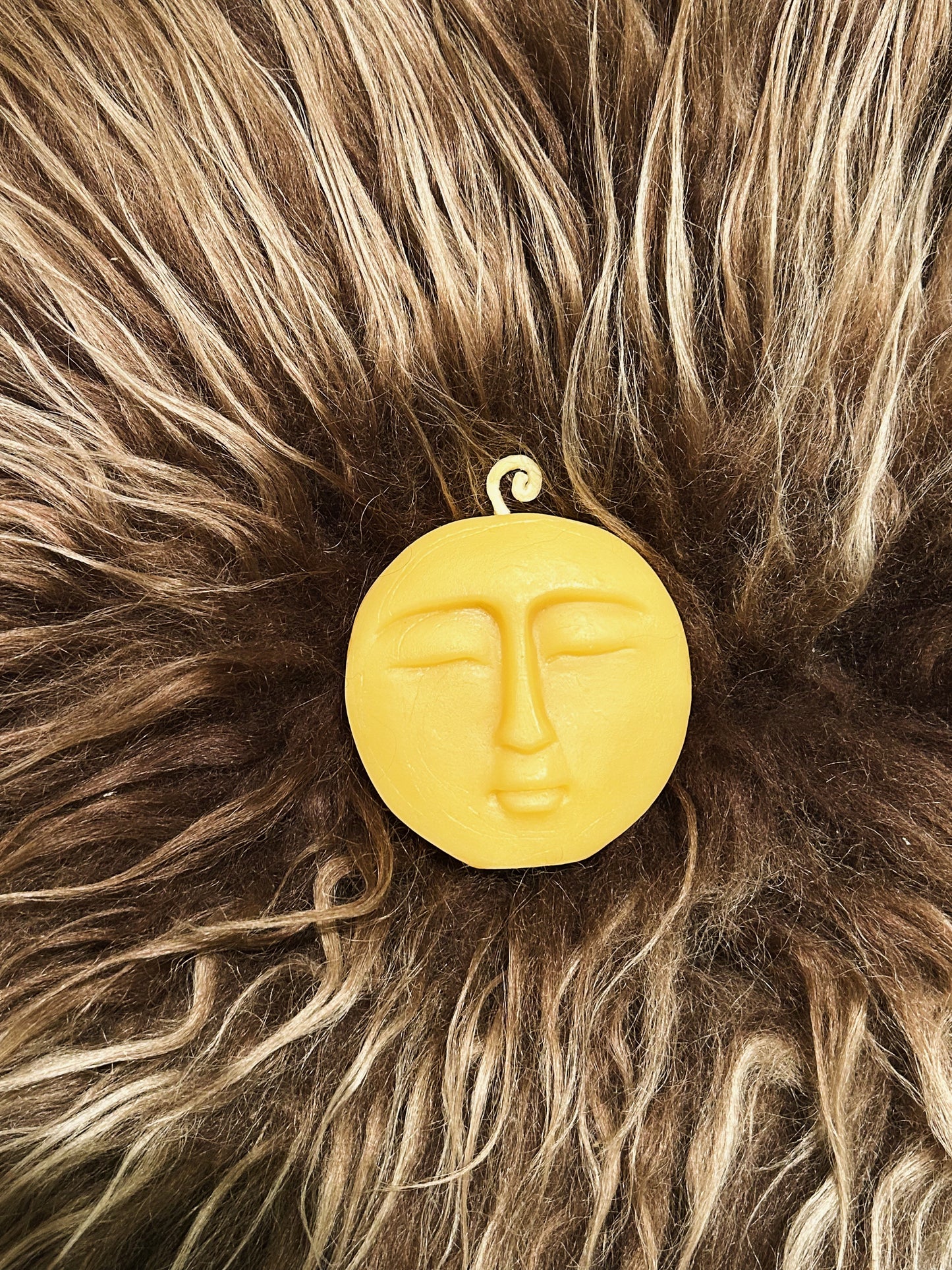 Beeswax moon candle on brown sheepskin.