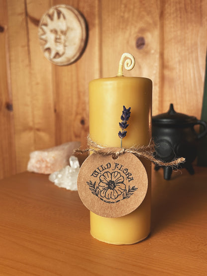 Beeswax pillar candle decorated with lavender and twine. Cauldron and rose quartz in background. Whimsical squiggly wick.