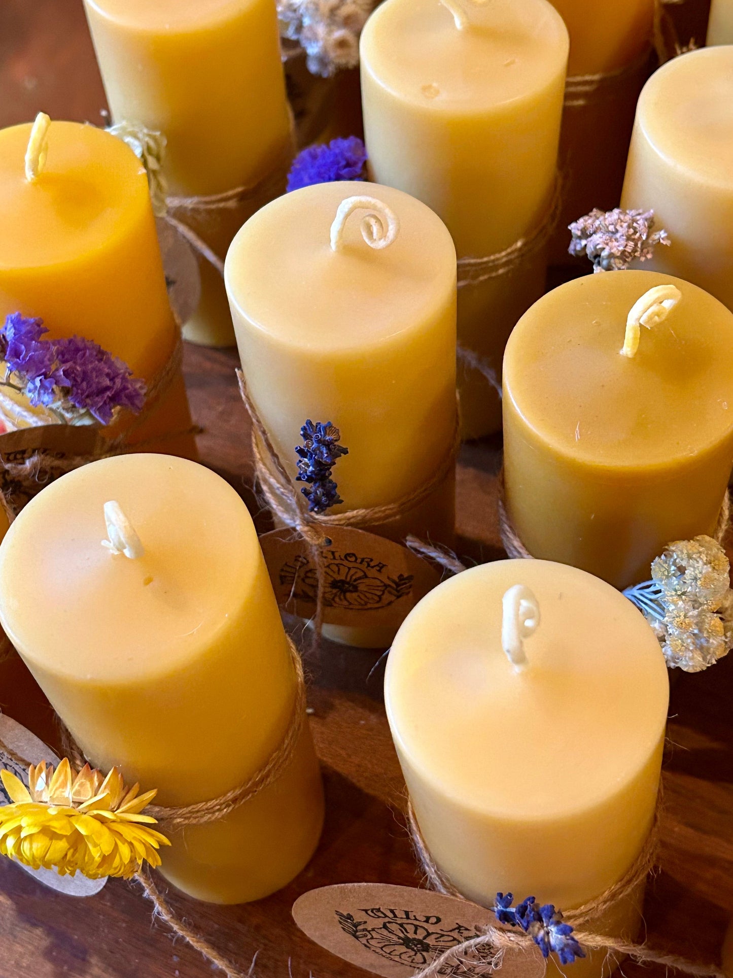 Beeswax candles with floral decorations on a wooden surface