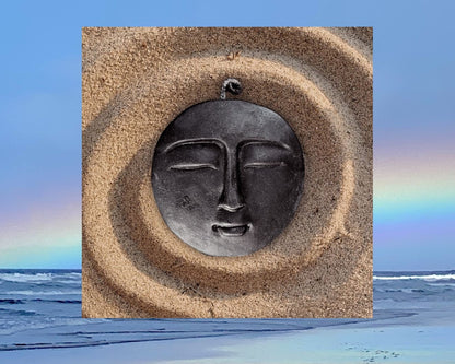 Black moon candle overlayed on spiral sand design and ocean with rainbow. 