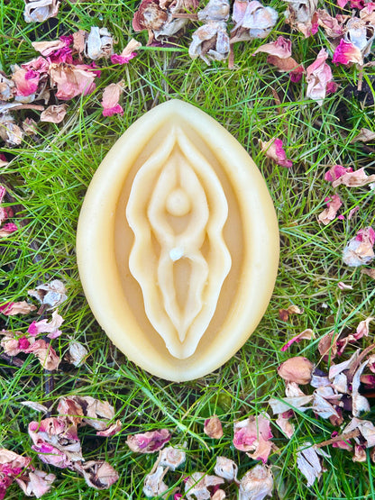 Beeswac vagina candle on grass with rose petals.